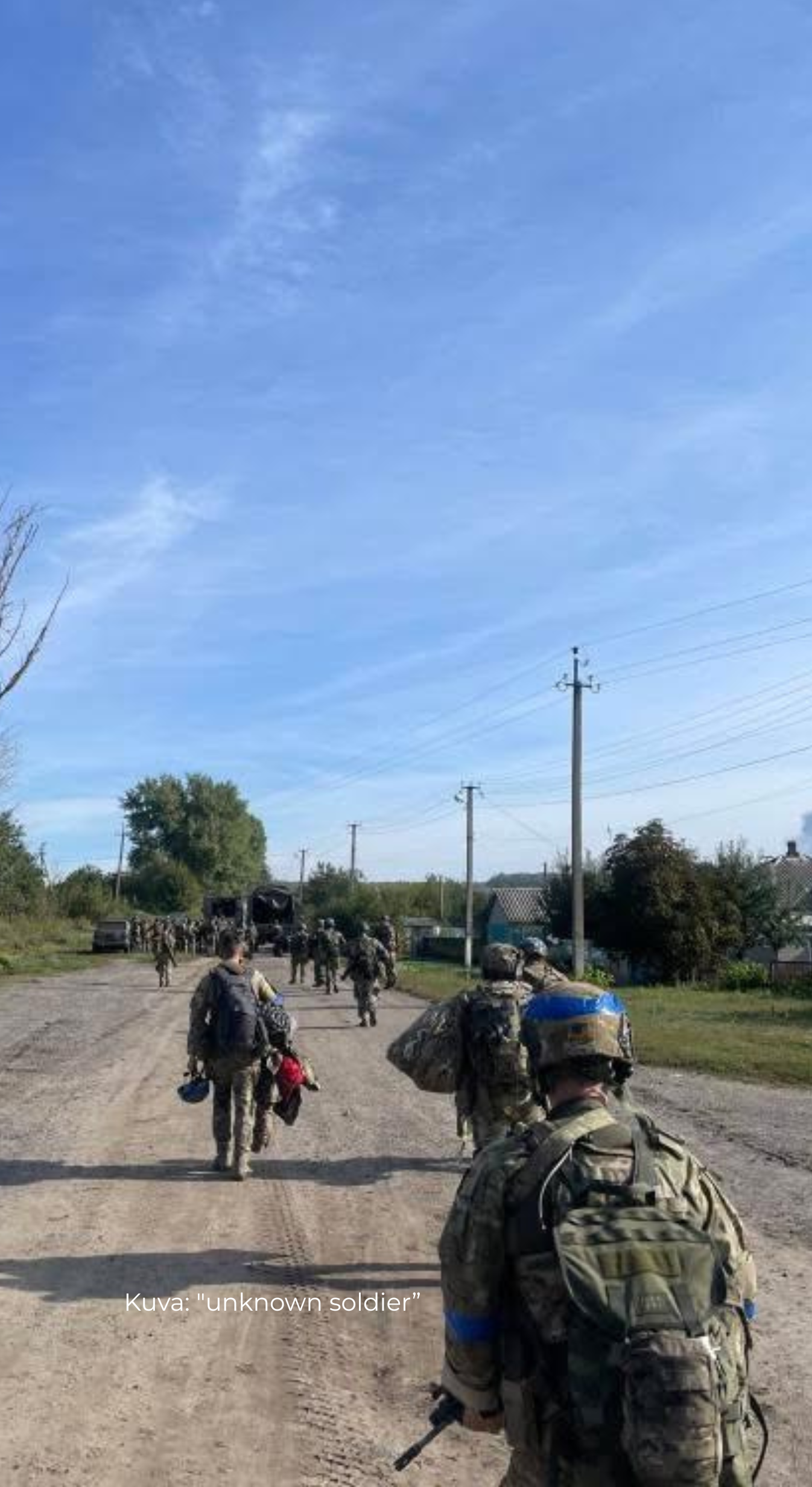 Group of Ukrainian soldiers in military gear with Savotta Kahakka backpacks walking along a road with a clear blue sky.