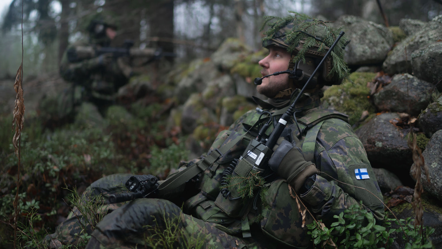 A soldier in camouflage gear sitting in a forest
