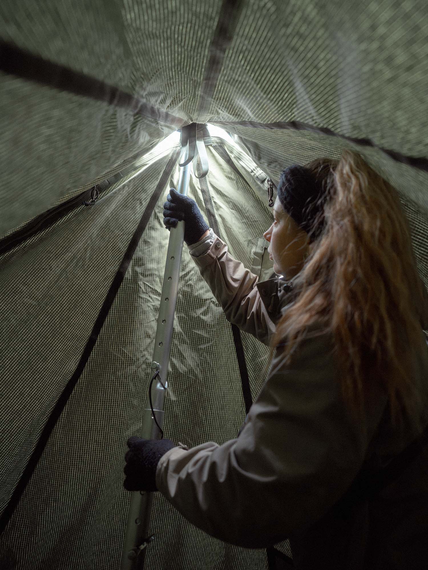 Person inside Savotta Hawu 8 tent setting up the center pole