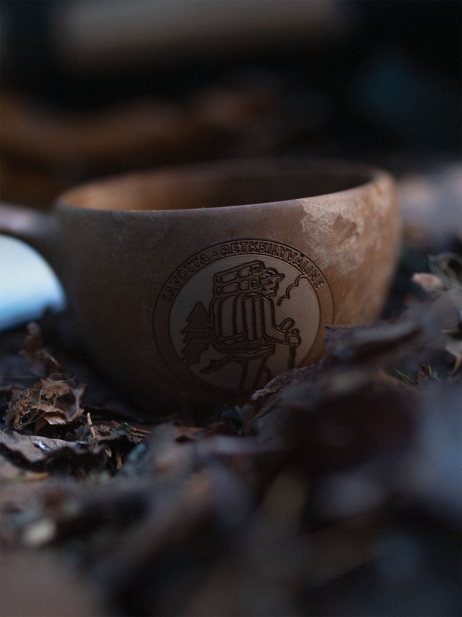 Brown Savotta x Kupilka cup with engraved Savotta logo on a natural background