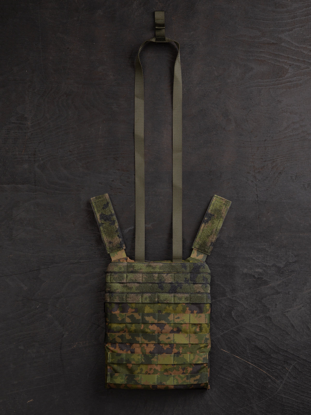 Savotta Varjelus plate carrier drag handle pulled out on a dark wooden surface.