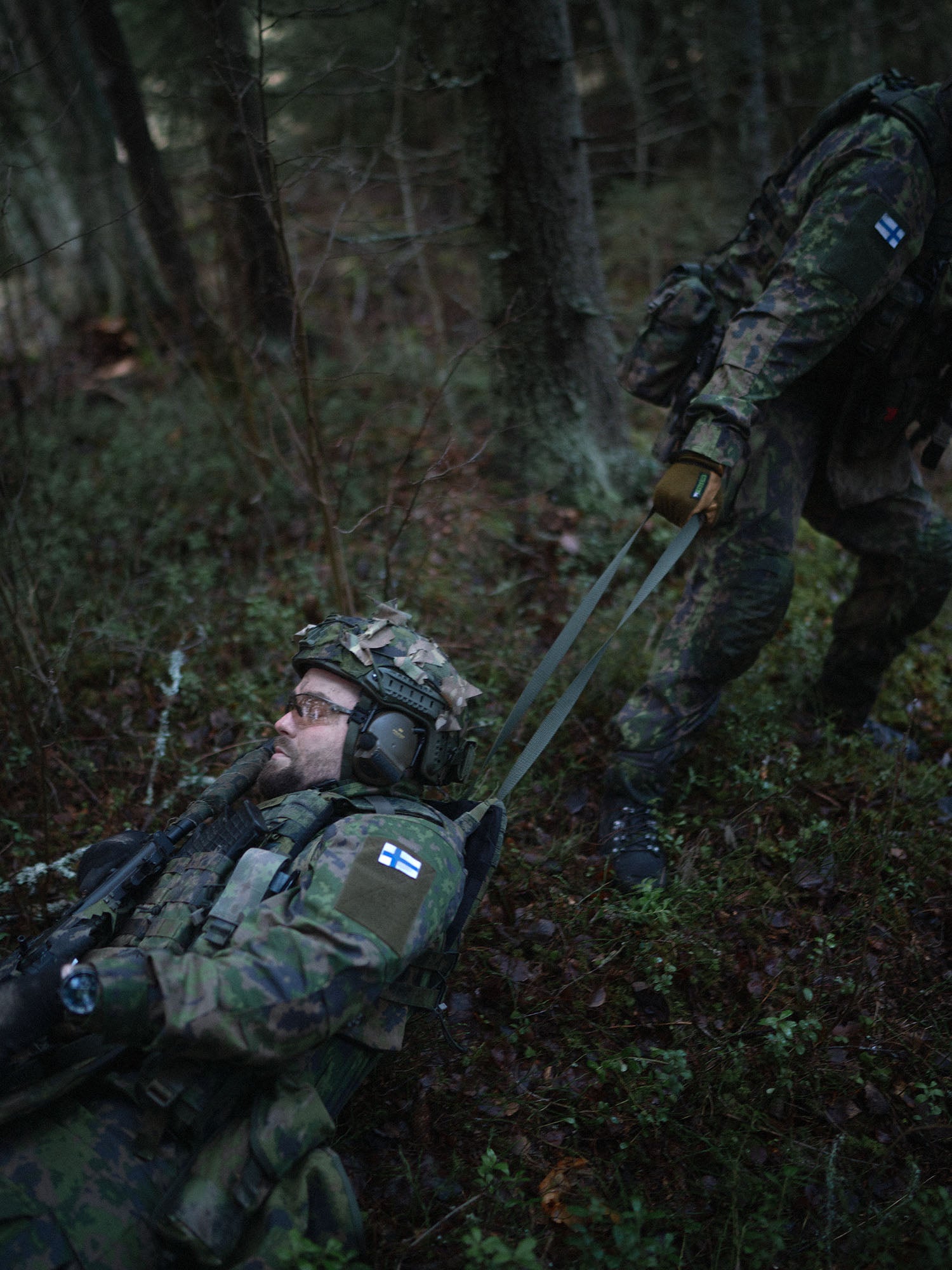 A soldier dragging a wounded soldier using a drag handle of a Savotta Varjelus plate carrier