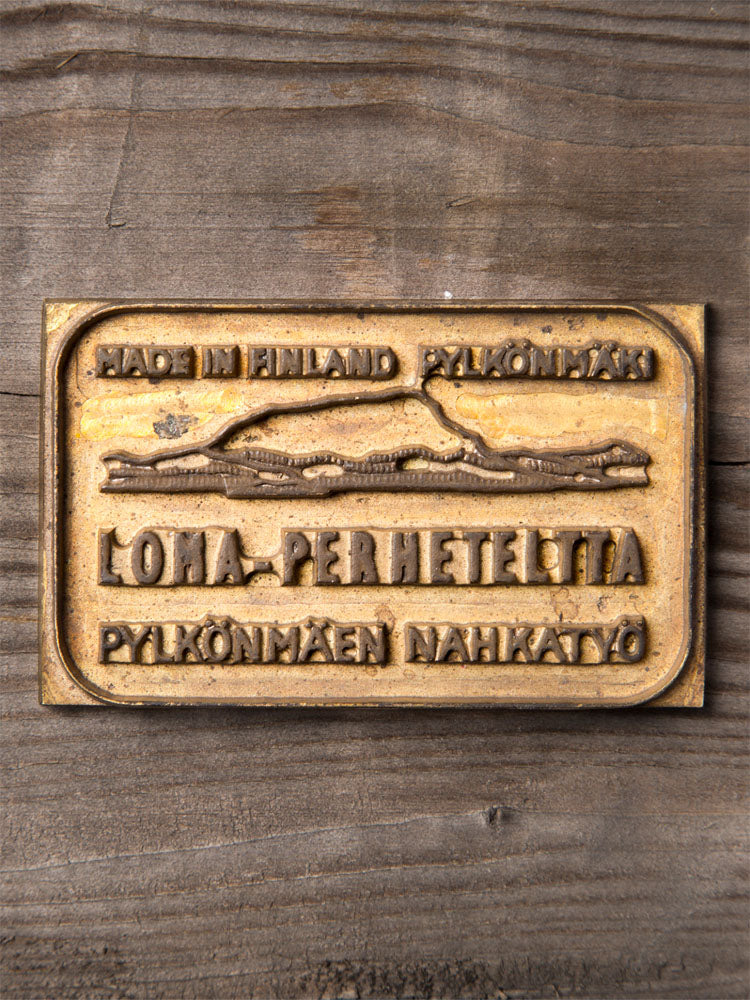 Bronze plaque with engraved text and a mountain design on a wooden background