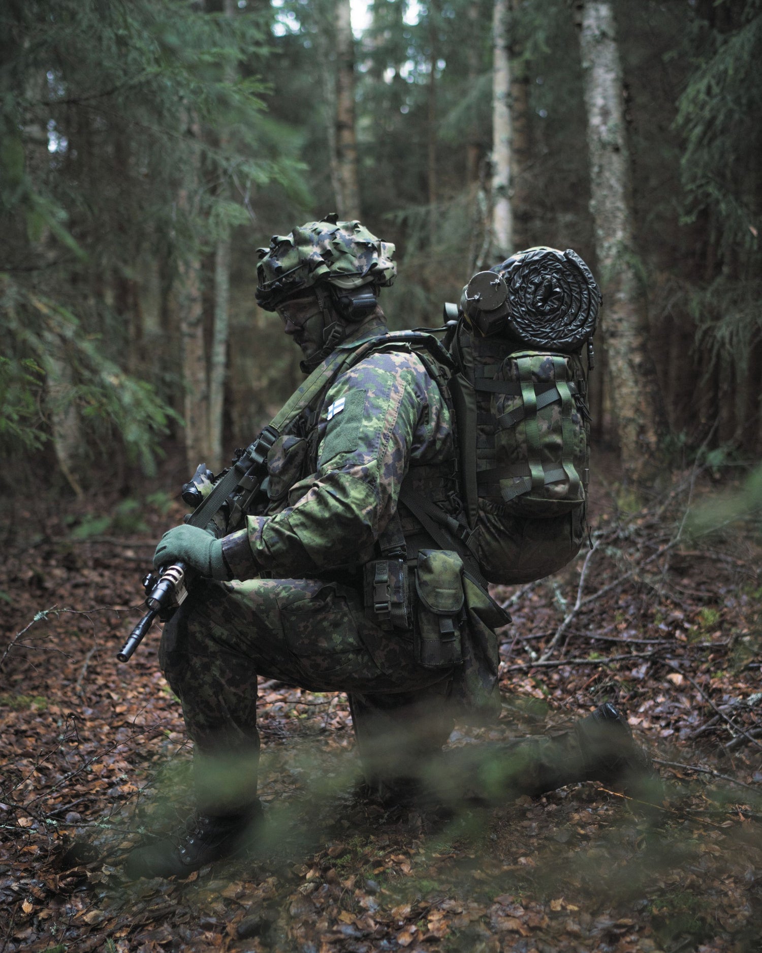 Person in camouflage gear with a backpack in a forest setting