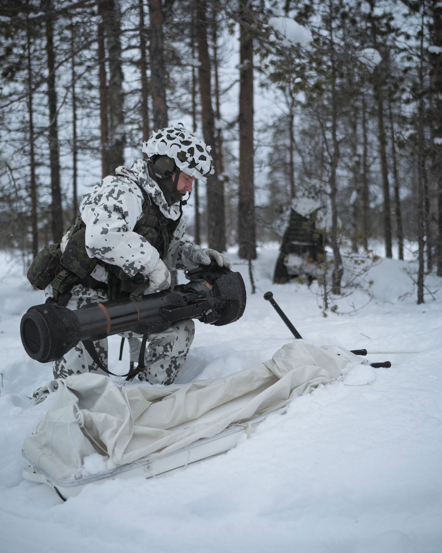 Person in camouflage gear with a large weapon in a snowy forest