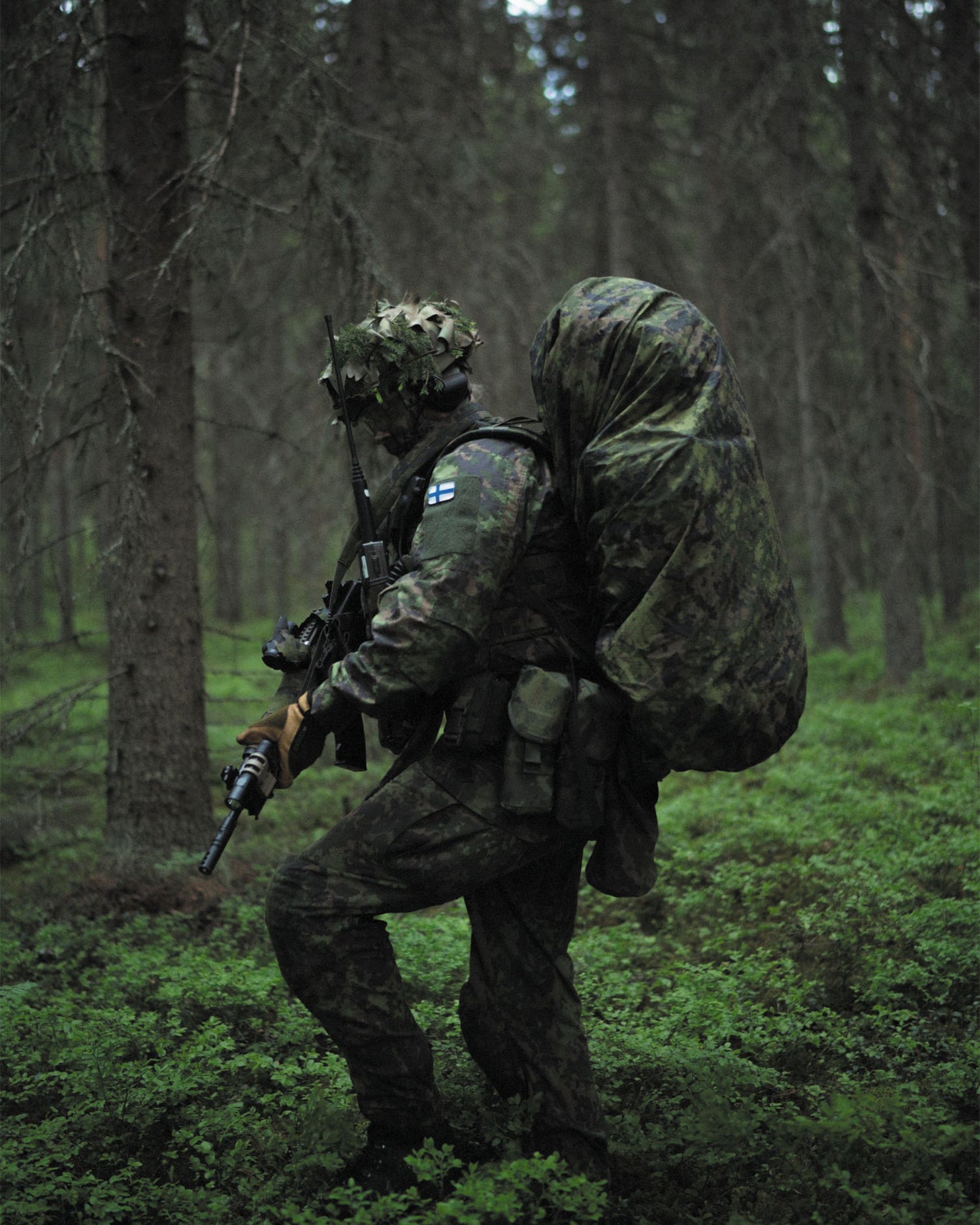 Person in military gear with a backpack in a forest