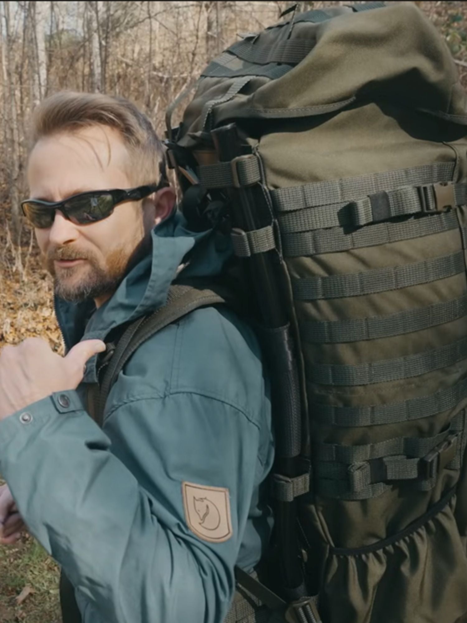 Man wearing sunglasses and a green jacket with a Savotta Jääkäri XL backpack outdoors