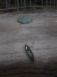 Canoe on a beach with Savotta Hawu 8 tent in the background
