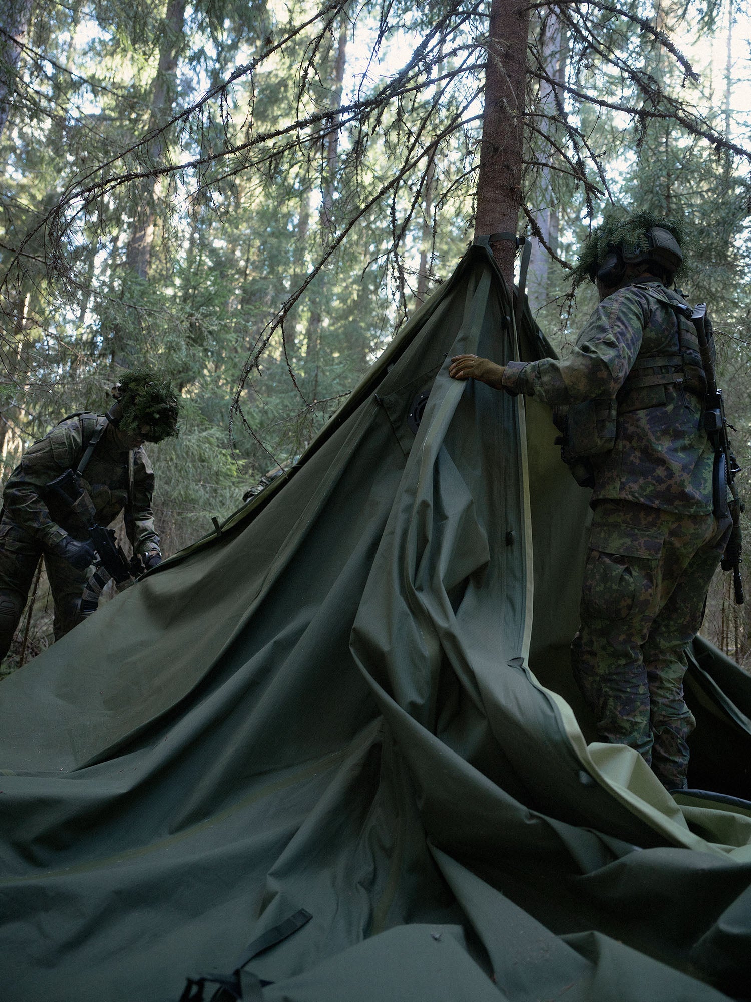 Two soldiers setting up a Savotta  Hawu 8 tent in a forested area