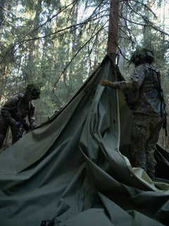 Two soldiers setting up a Savotta  Hawu 8 tent in a forested area