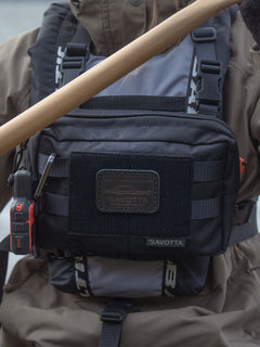 Black Savotta Rintamus chest pack with a Savotta leather patch in black, attached to a person wearing a brown jacket.