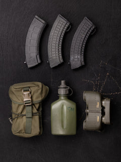 Savotta Lidded GP pouch 3x4 and a set of military supplies that fit into the pouch including magazines, a canteen, and binoculars on a dark wooden surface.