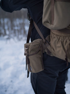 Close-up of a brown Savotta Lidded GP pouch 3x4 attached to a backapck in a snowy scenery