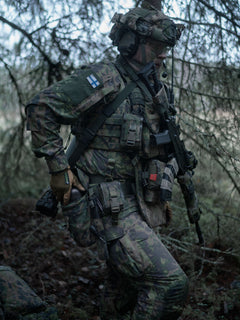 Soldier in camouflage gear with a rifle in a forest setting putting an item into a Savotta Lidded GP pouch 3x4.