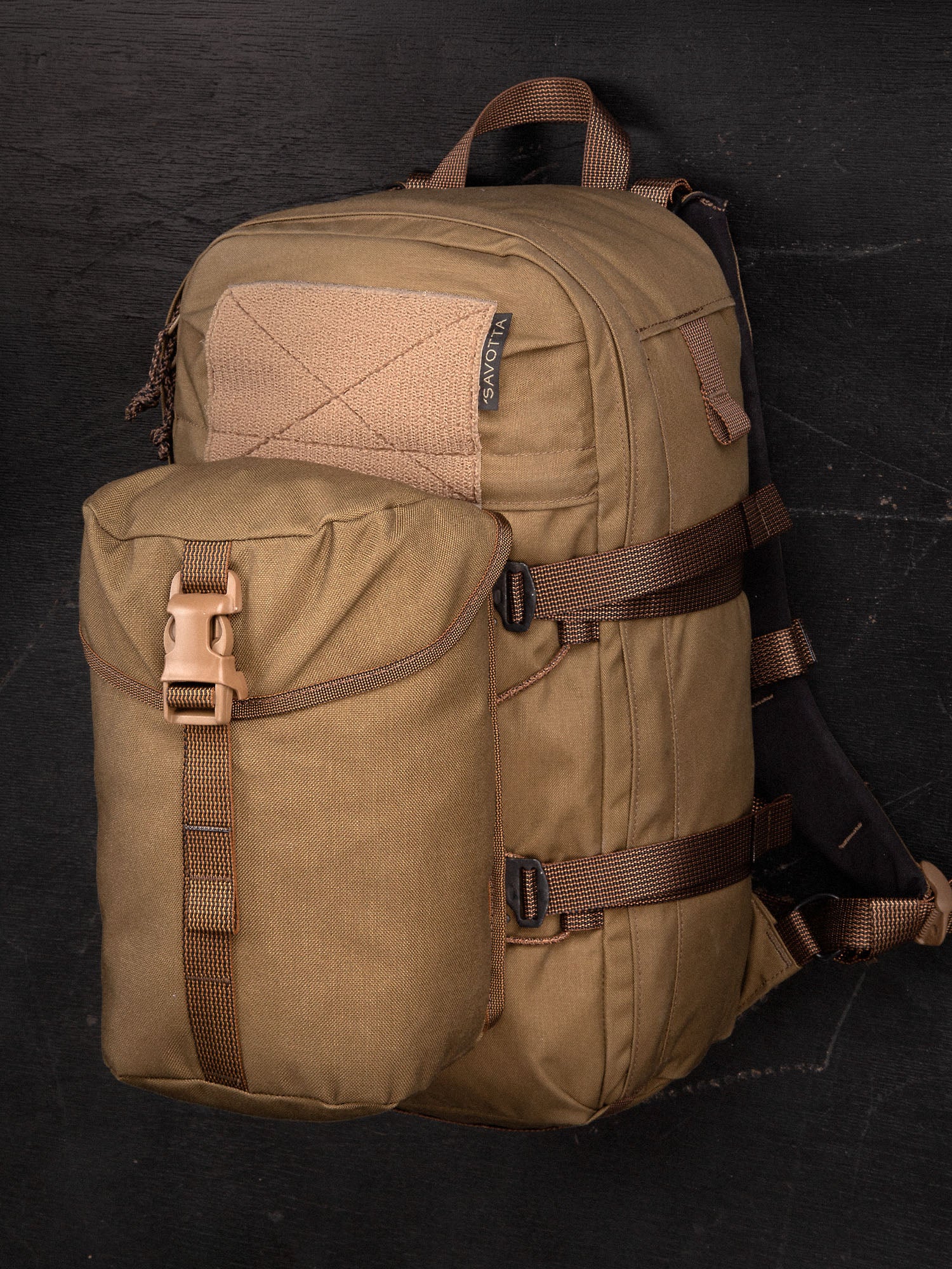 Savotta lidded GP pouch 4x5 attached to a Savotta Niukka 20L backpack on a dark background