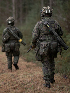 Two soldiers in camouflage uniforms with Savotta Lidded GP pouches 4x5 attached walking through a forested area.