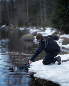Person fishing wearing a Savotta Rintamus chest pack with snow and trees in the background