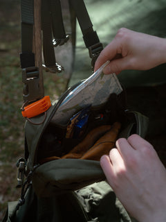 Person opening a green Savotta Rintamus chest pack in the outdoors.
