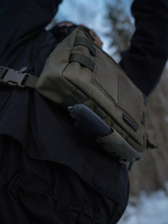 Person wearing a greenSavotta Rintamus chest pack with a knife attached to the bottom on a snowy background