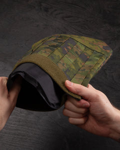 Savotta Varjelus groin flap with a Savotta Sioen 25x30cm NIJ IIA panel inside of it on a dark wooden surface