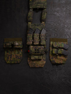 Three different setups you can do with a Savotta Varjelus groin flap. The Savotta plate carrier is being spread out on a dark wooden background. There are different Savotta mag pouches and Savotta S-IFAK horizontal mount attached to the groin flaps.