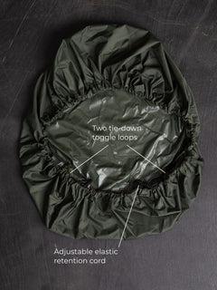 Savotta backpack cover 30L lying on a dark wooden surface with labels