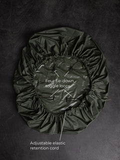 Savotta backpack cover 50L lying on a dark wooden surface with labels