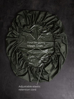 Savotta backpack cover 80L lying on a dark wooden surface with labels