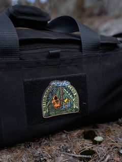 Black Keikka duffel bag with a Savotta Better gear less misery patch on a forest floor