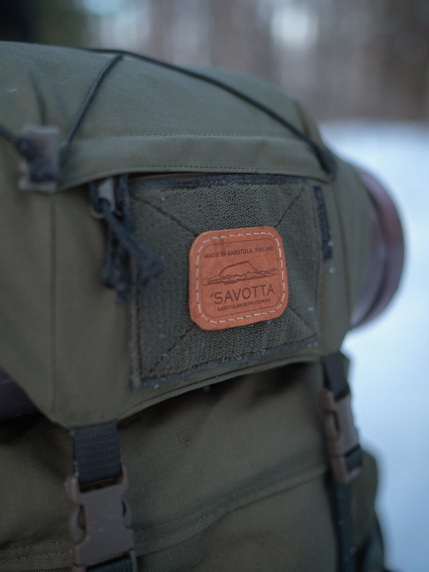 Green Savotta Kantamus backpack with a leather patch labeled 'Savotta' on a blurred background