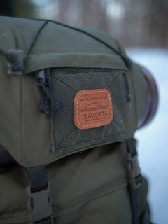 Green Savotta Kantamus backpack with a leather patch labeled 'Savotta' on a blurred background