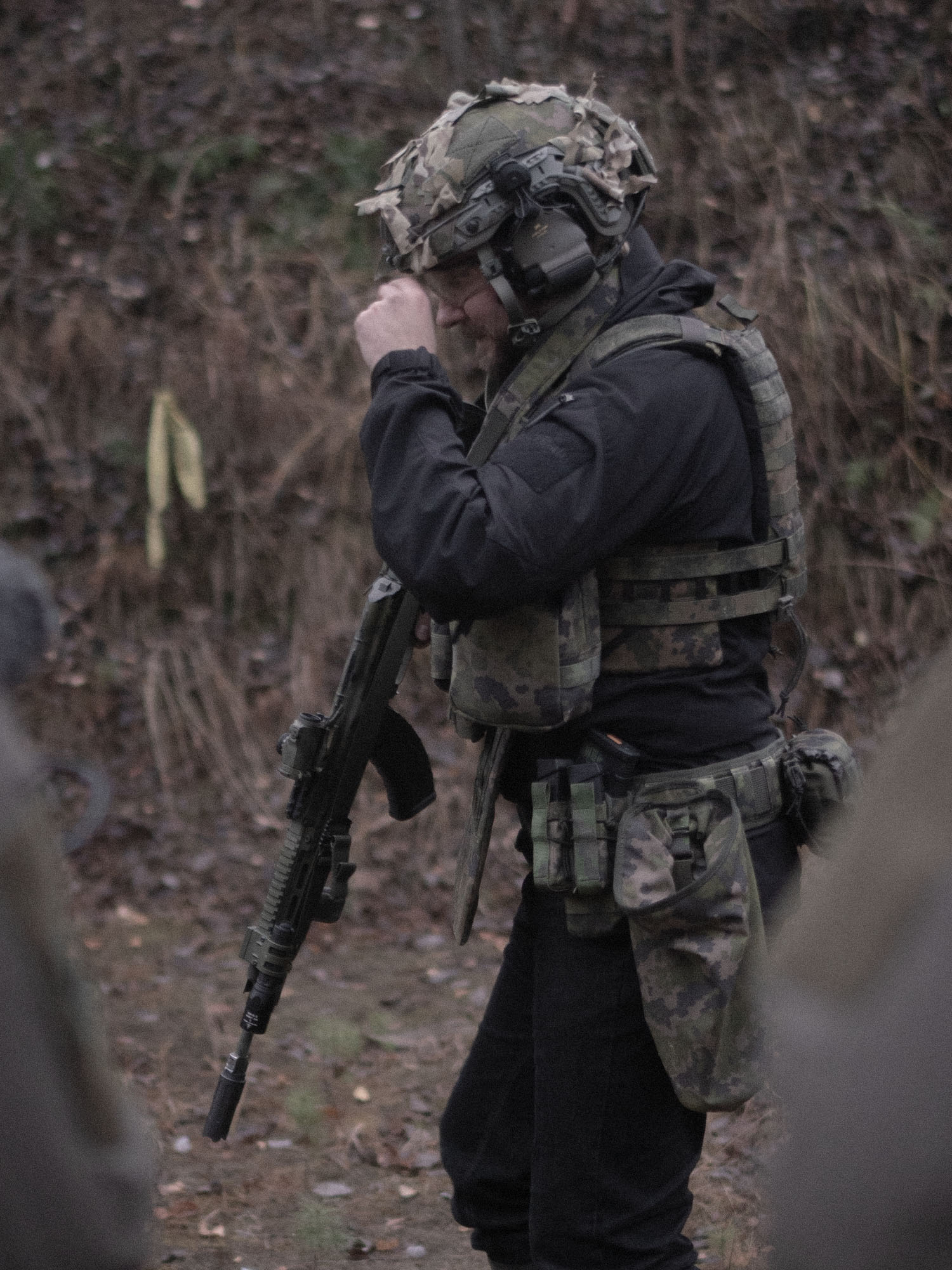 Person in tactical gear with Savotta open top pistol mag pouches attached holding a rifle in a natural setting