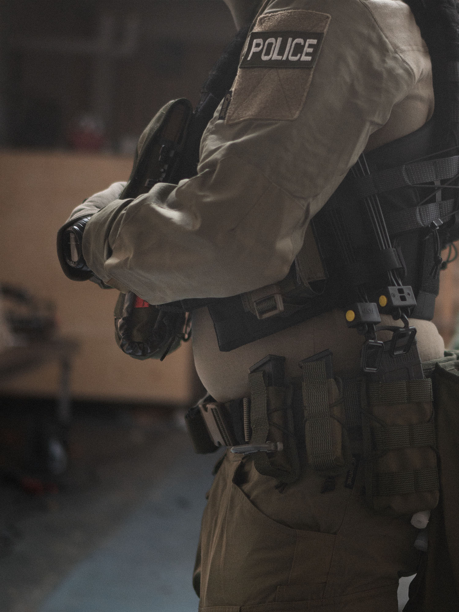 Person in tactical police gear with Savotta open top pistol magazine pouches attached to the waist, blurred indoor background