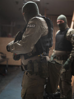 Person in tactical police gear with Savotta open top pistol mag pouches attached to the waist in an indoor setting