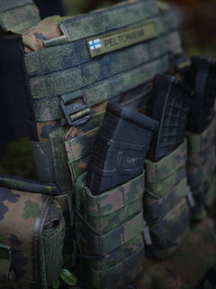 Close-up of a Savotta Varjelus plate carrier with mag pouches attached, in a forest setting