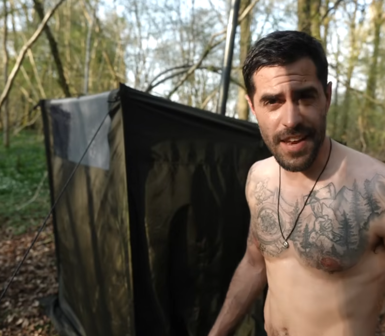 Influencer TA Outdoors standing in front of a Savotta Hiisi 2 sauna tent in a forest